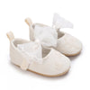 Pair of light beige lace-trimmed baby girl moccasin shoes with white bows