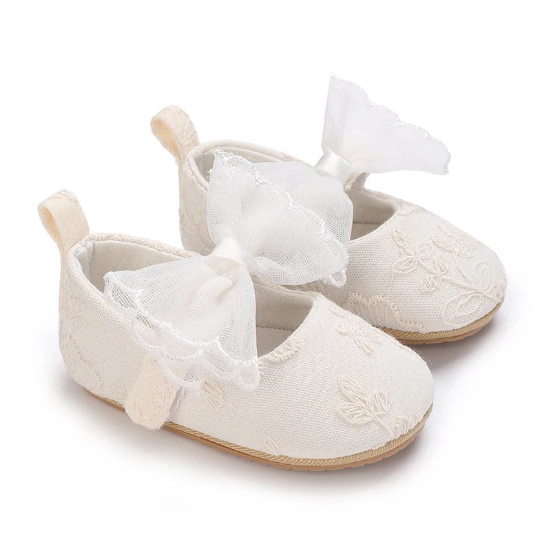 Pair of light beige lace-trimmed baby girl moccasin shoes with white bows