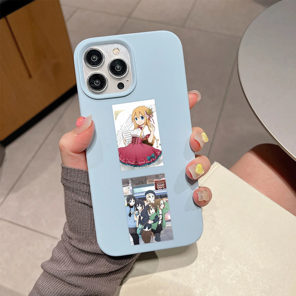 A light blue smartphone case featuring K-ON! anime stickers, including a guitar girl and characters from the series.