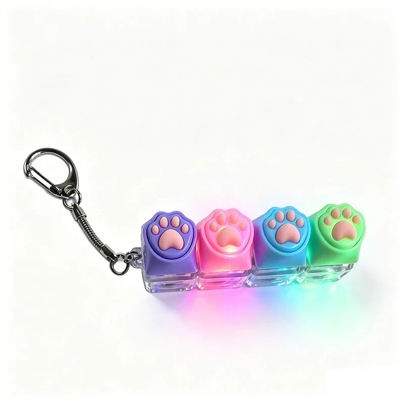 A keychain fidget toy shaped like a paw print in purple, pink, and blue, illuminated by an LED light.