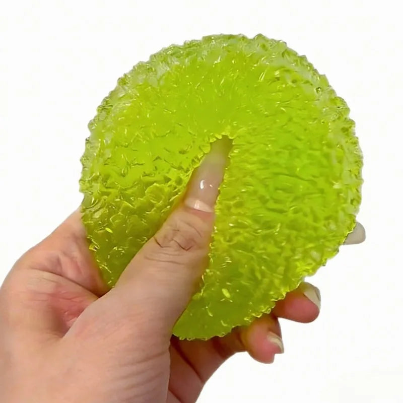 A hand is holding a bright lime green squishy ice ball mochi fidget toy, showing its textured surface.
