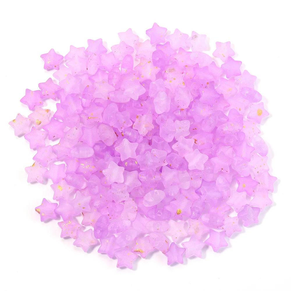 A pile of small, transparent pink and purple star-shaped acrylic beads for jewelry making.