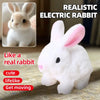 A realistic electric rabbit plush toy with pink ears and black eyes is shown on a textured surface.