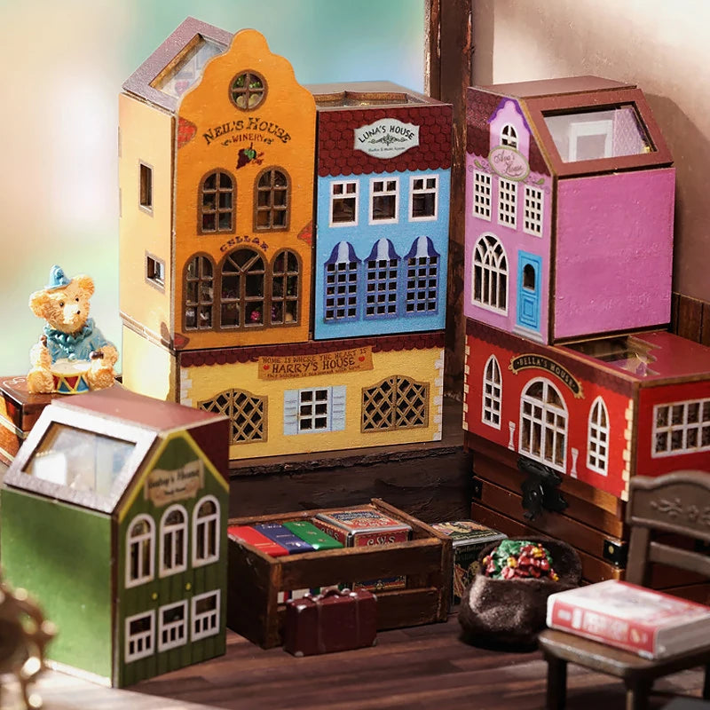 A collection of wooden miniature dollhouses and houses in various colors and styles displayed on a wooden surface.