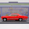 A red 1967 Chevrolet Impala diecast model car in a pull-back action pose on a gray surface.