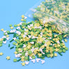 A pile of green and yellow cartoon polymer clay slices for slime and craft projects, with some inside a clear plastic bag.