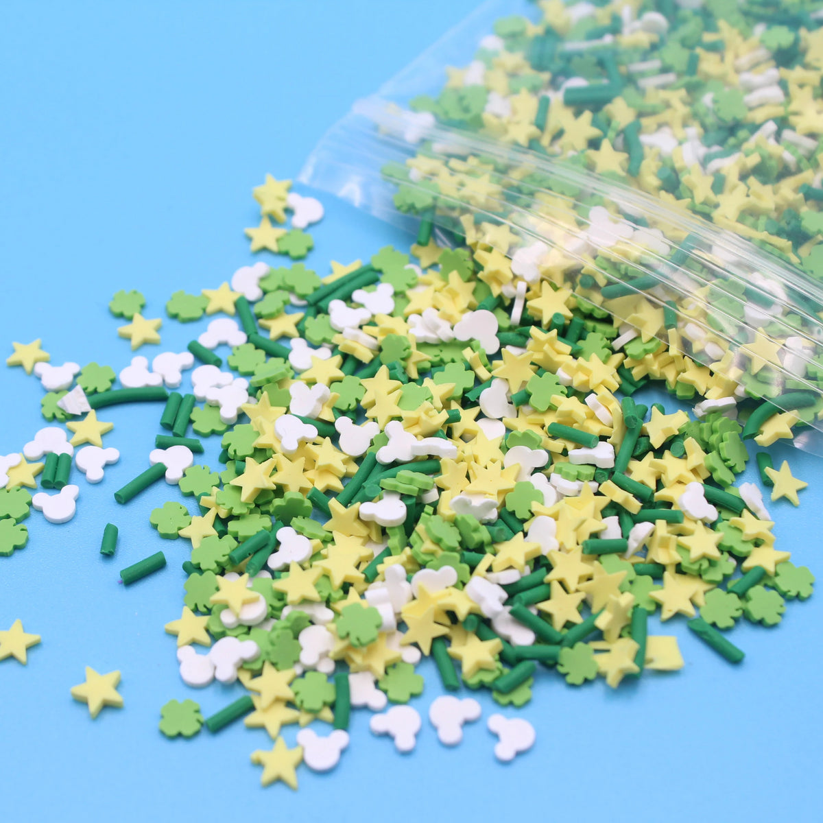A pile of green and yellow cartoon polymer clay slices for slime and craft projects, with some inside a clear plastic bag.