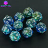 A collection of ten glittery blue and green polyhedral dice set on a dark surface.