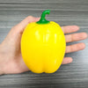 A hand holds a bright yellow bell pepper with a green stem, used as a fidget toy.