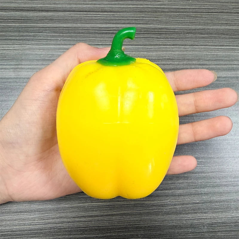A hand holds a bright yellow bell pepper with a green stem, used as a fidget toy.