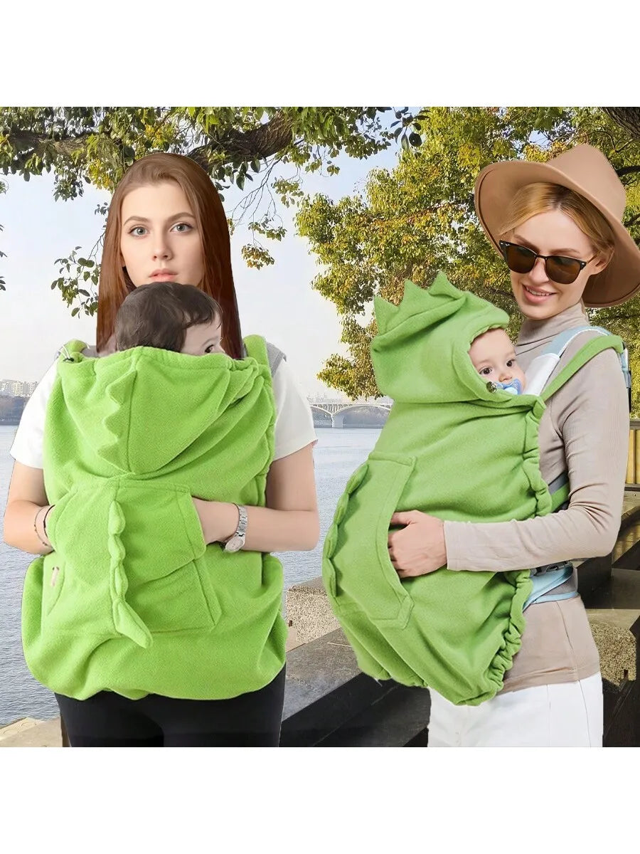A woman is holding a green baby windproof cape blanket with a dinosaur design for a baby.