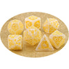 A set of yellow and white dragon-inspired polyhedral dice, including d6s, d8s, and a triangle die, scattered on gold glitter.