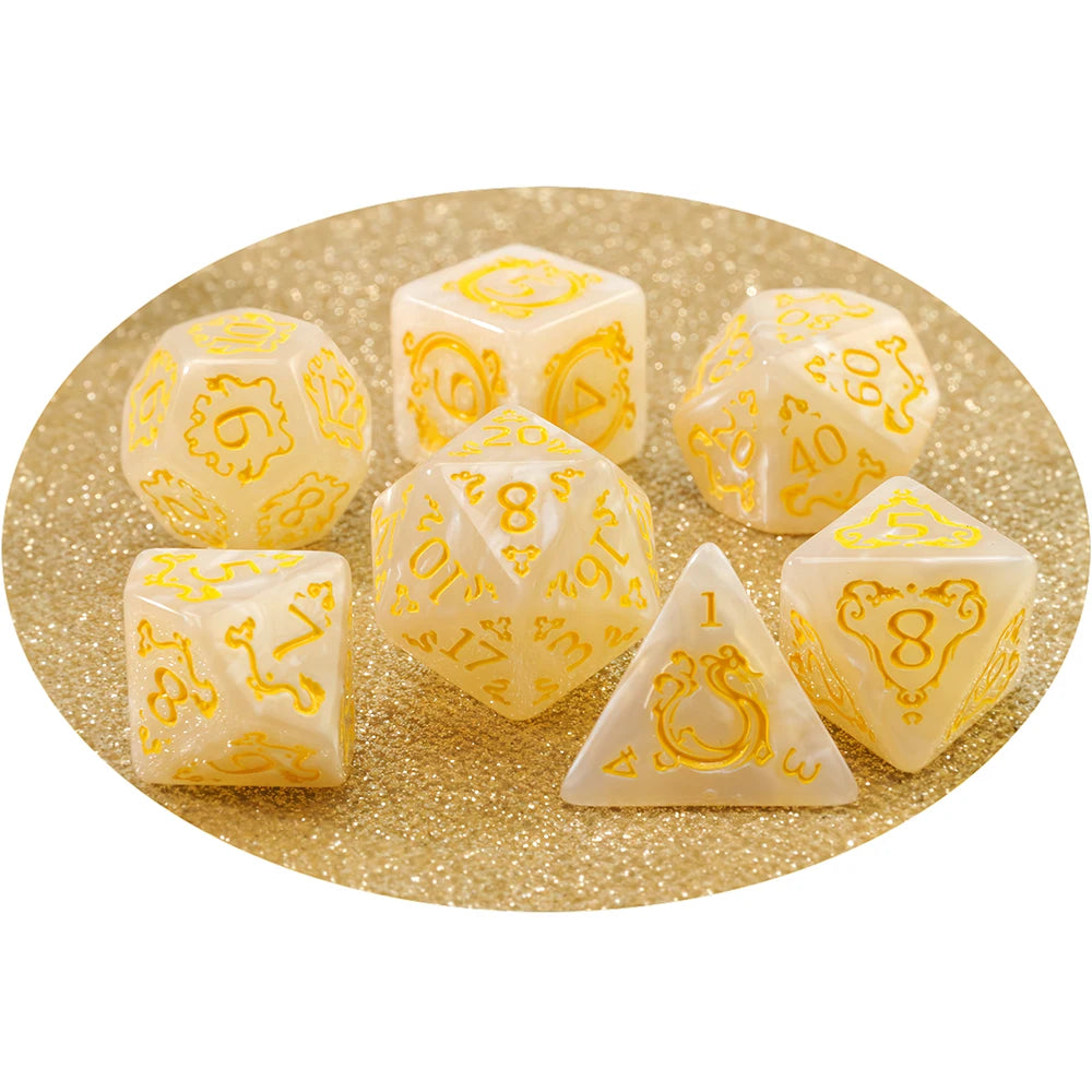 A set of yellow and white dragon-inspired polyhedral dice, including d6s, d8s, and a triangle die, scattered on gold glitter.