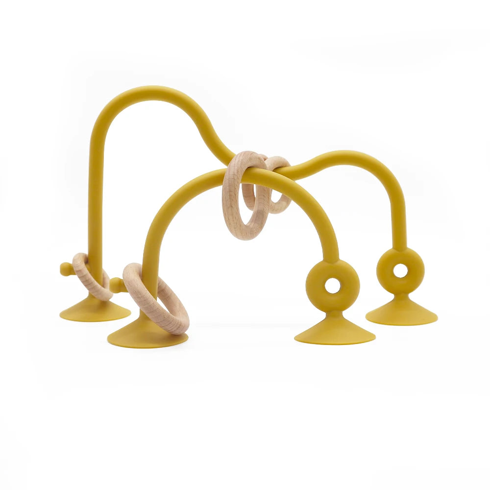 A yellow silicone teether ring with a curved handle and a looped end is shown against a white background.
