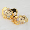 A gold-colored pacifier and clip set featuring a crystal charm engraved with the name Jose