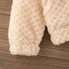Close-up of a cream-colored, fluffy baby girl's plush hooded winter jacket sleeve.