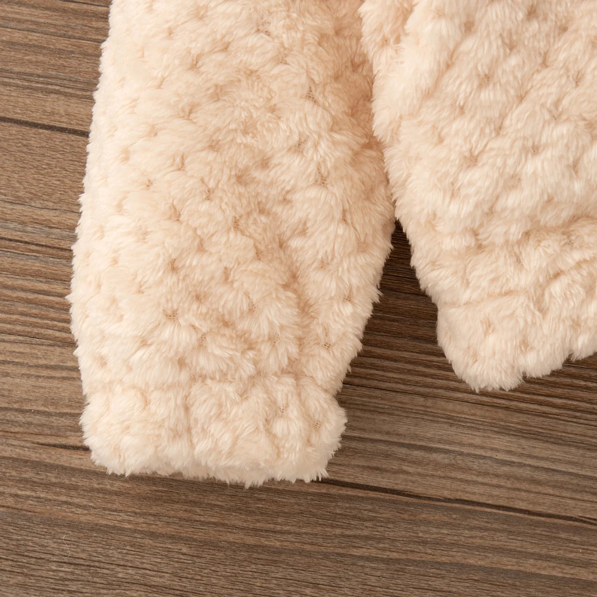 Close-up of a cream-colored, fluffy baby girl's plush hooded winter jacket sleeve.