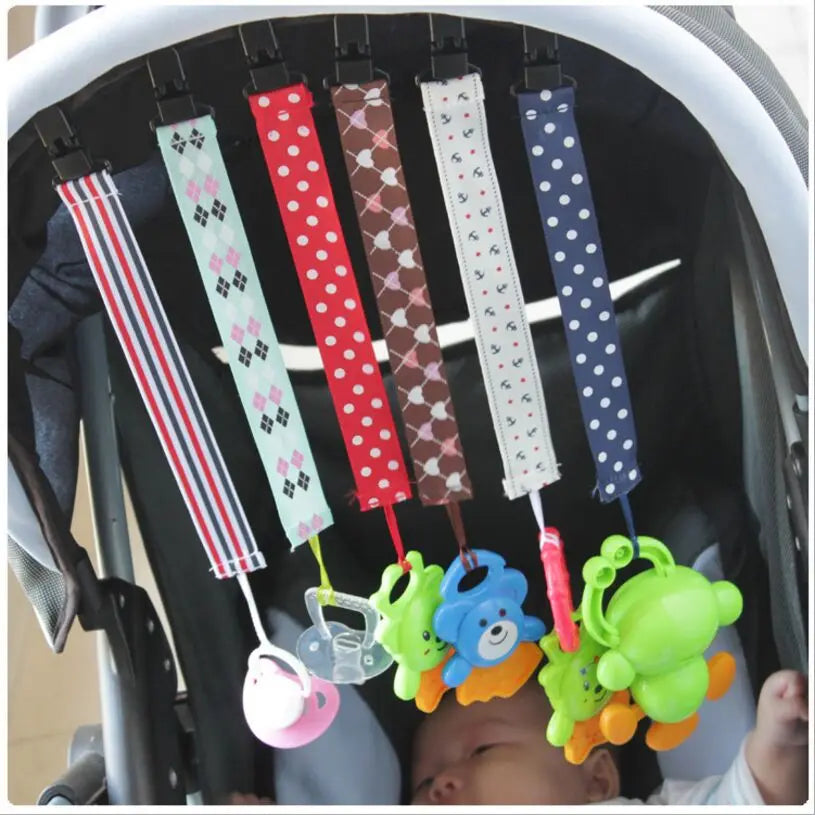 A set of four soft pacifier clips with double-sided prints are hanging inside a baby carrier.