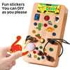 A wooden busy board for DIY stickers featuring various buttons, switches, and a dinosaur theme.