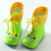 A pair of bright lime green rain boots with yellow trim and a cute frog design.