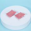 Two red and white striped pillows displayed on a white circular platform.