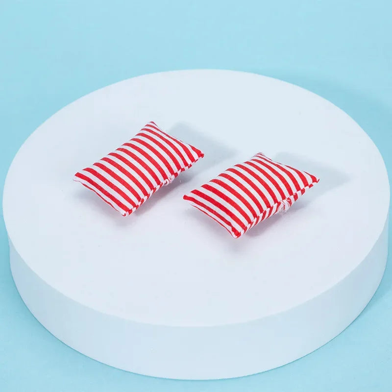 Two red and white striped pillows displayed on a white circular platform.