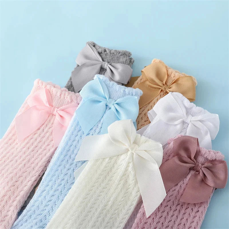 A collection of baby girl lace knee socks with bows in various pastel colors including pink, blue, lavender, and beige.