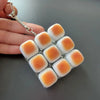 A set of orange and white LED mechanical keycap fidget charms attached to a silver keychain ring.