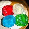 Three colorful squishy stress balls in red, white, and green resting on a white plate.