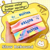 Eine Hand hält ein rosa und ein gelbes Butter-Pressspielzeug vor einem gelben Hintergrund.