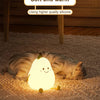 A soft, glowing pear-shaped night light resembling a cat is resting on a beige carpet.