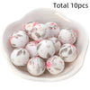 A bowl filled with ten pink and white floral printed silicone beads for DIY jewelry making