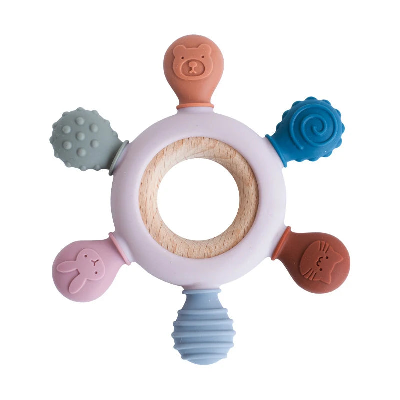 A silicone baby teether shaped like a rudder with a wooden ring and various colored silicone attachments.
