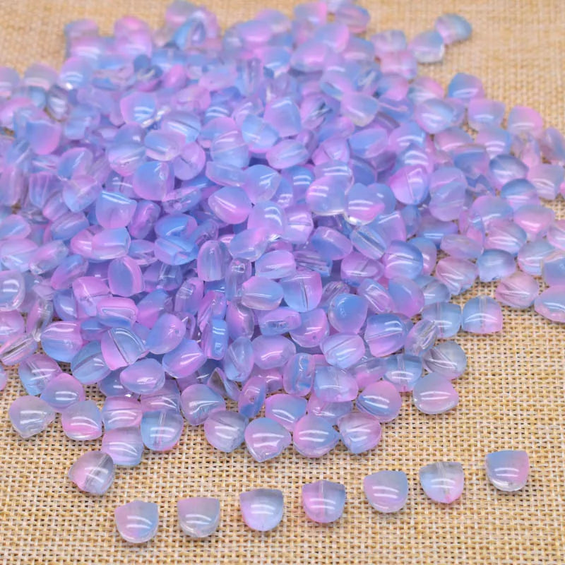 A pile of iridescent purple and pink glass beads scattered on a beige fabric surface.