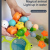 A hand places various colorful, light-up animal toys into water to show their magical glow.