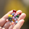 A hand holds a cluster of colorful 6mm glass round beads for DIY jewelry making