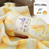 Three skeins of gradient acrylic yarn in yellow and white are displayed on a wooden background.