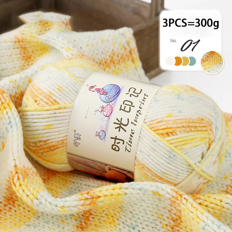 Three skeins of gradient acrylic yarn in yellow and white are displayed on a wooden background.