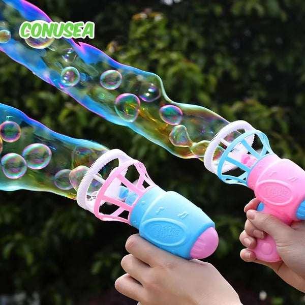 A hand is holding a pink manual bubble gun filled with iridescent liquid bubbles against a blurred green background.