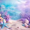 A collection of sea creatures and shells, including starfish and various seashells, arranged on sand with purple and blue flo