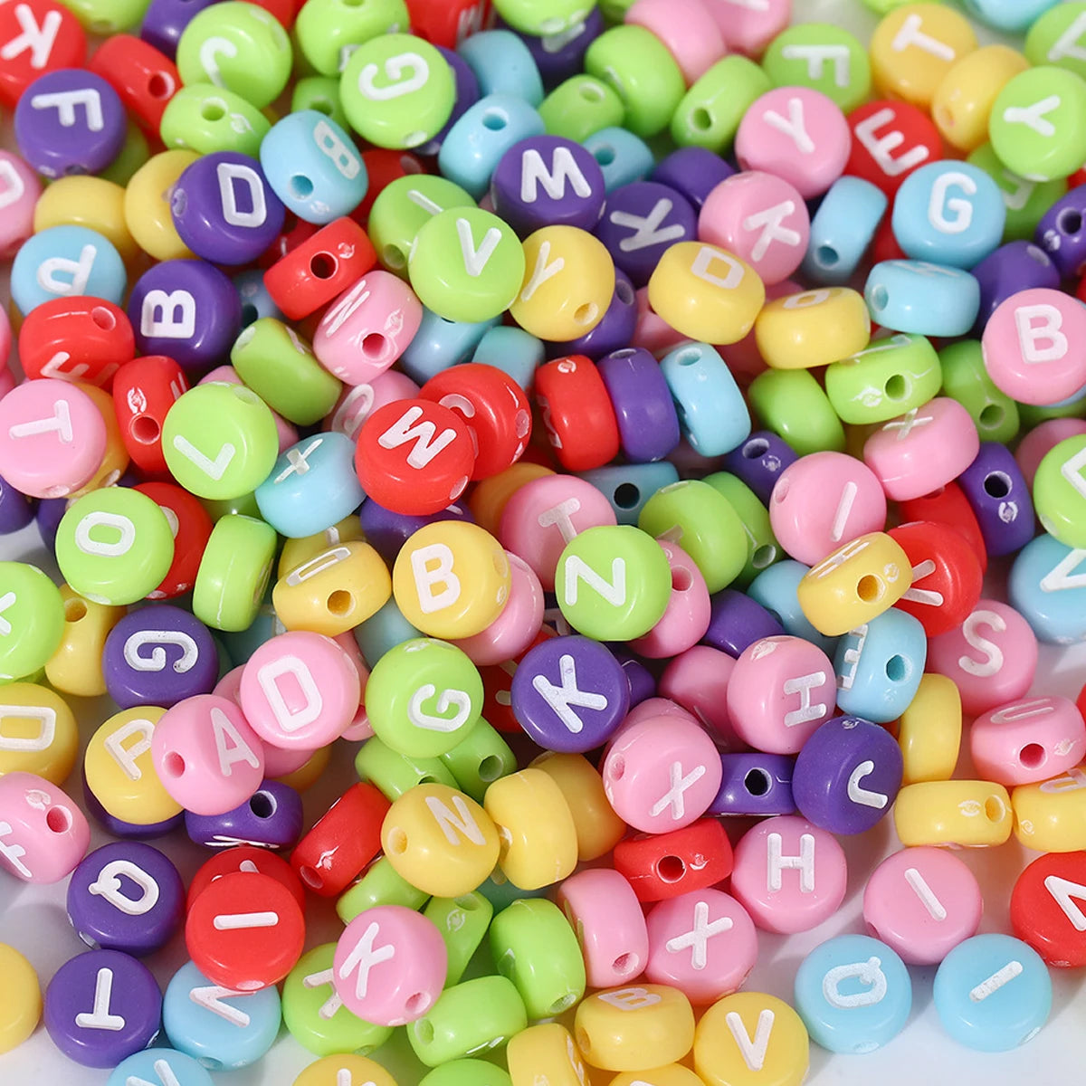 A close-up shot of a large collection of round acrylic alphabet beads in various colors like pink, green, yellow, and purple.