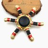 A metal fidget spinner with a star shape featuring gold and red accents and a black center.