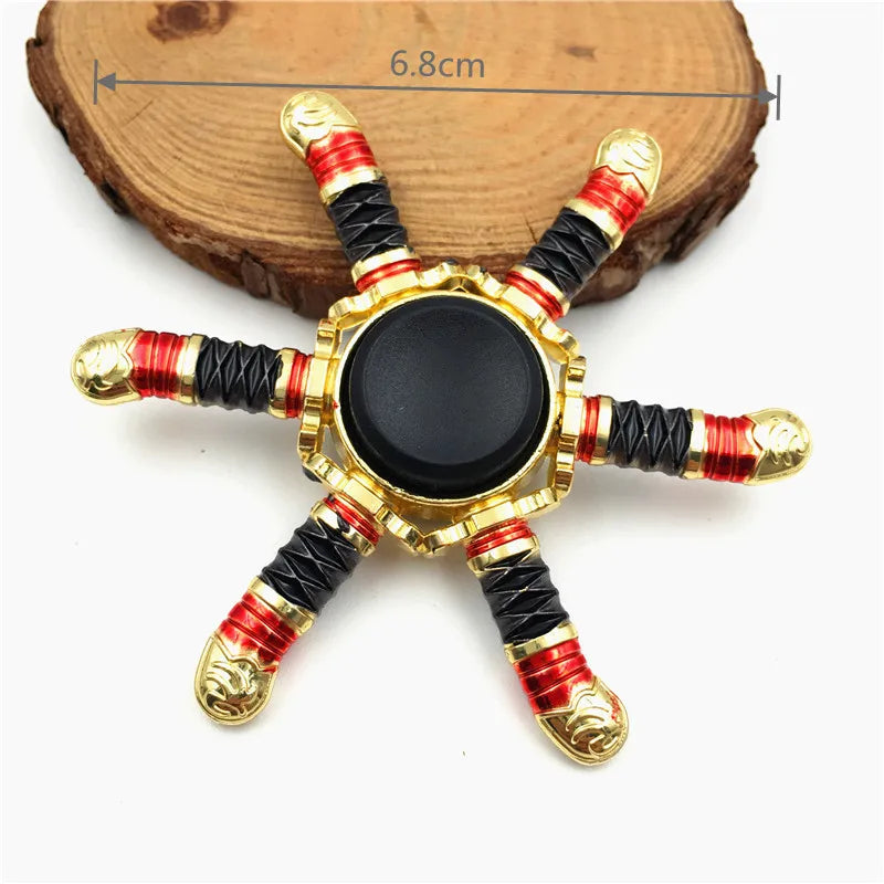 A metal fidget spinner with a star shape featuring gold and red accents and a black center.