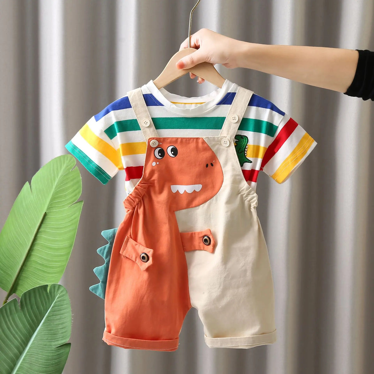 A child-sized dinosaur outfit set featuring an orange dinosaur-shaped romper and a striped shirt.