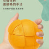 A hand holds an orange fruit-shaped 3x3 puzzle cube, demonstrating a method for teaching logic and imagination.