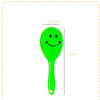 A bright green plastic mini maracas shaker toy with a smiley face, shown next to a measurement scale.