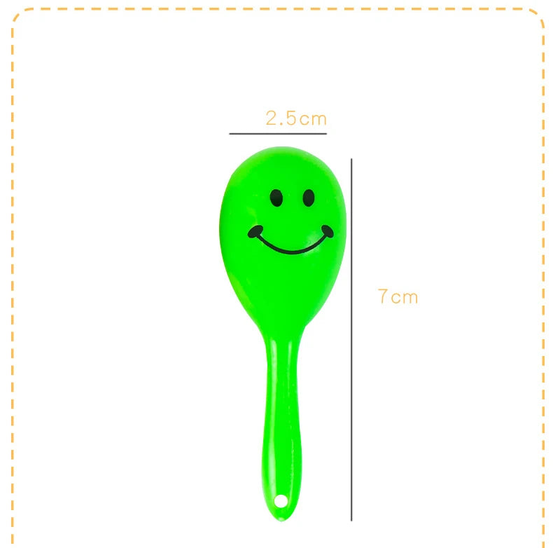 A bright green plastic mini maracas shaker toy with a smiley face, shown next to a measurement scale.