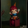 A collectible figure of a clown with red hair and a striped hat, featuring a skull accessory.