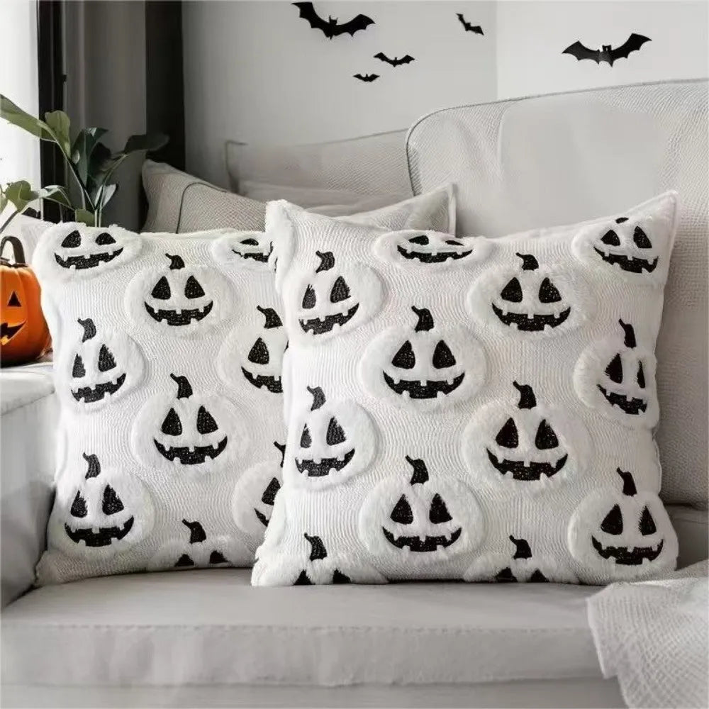 A set of white Halloween pillow covers featuring black carved pumpkin designs on a light gray sofa.