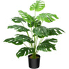 A vibrant green faux Monstera palm plant with large, deeply lobed leaves in a black pot.